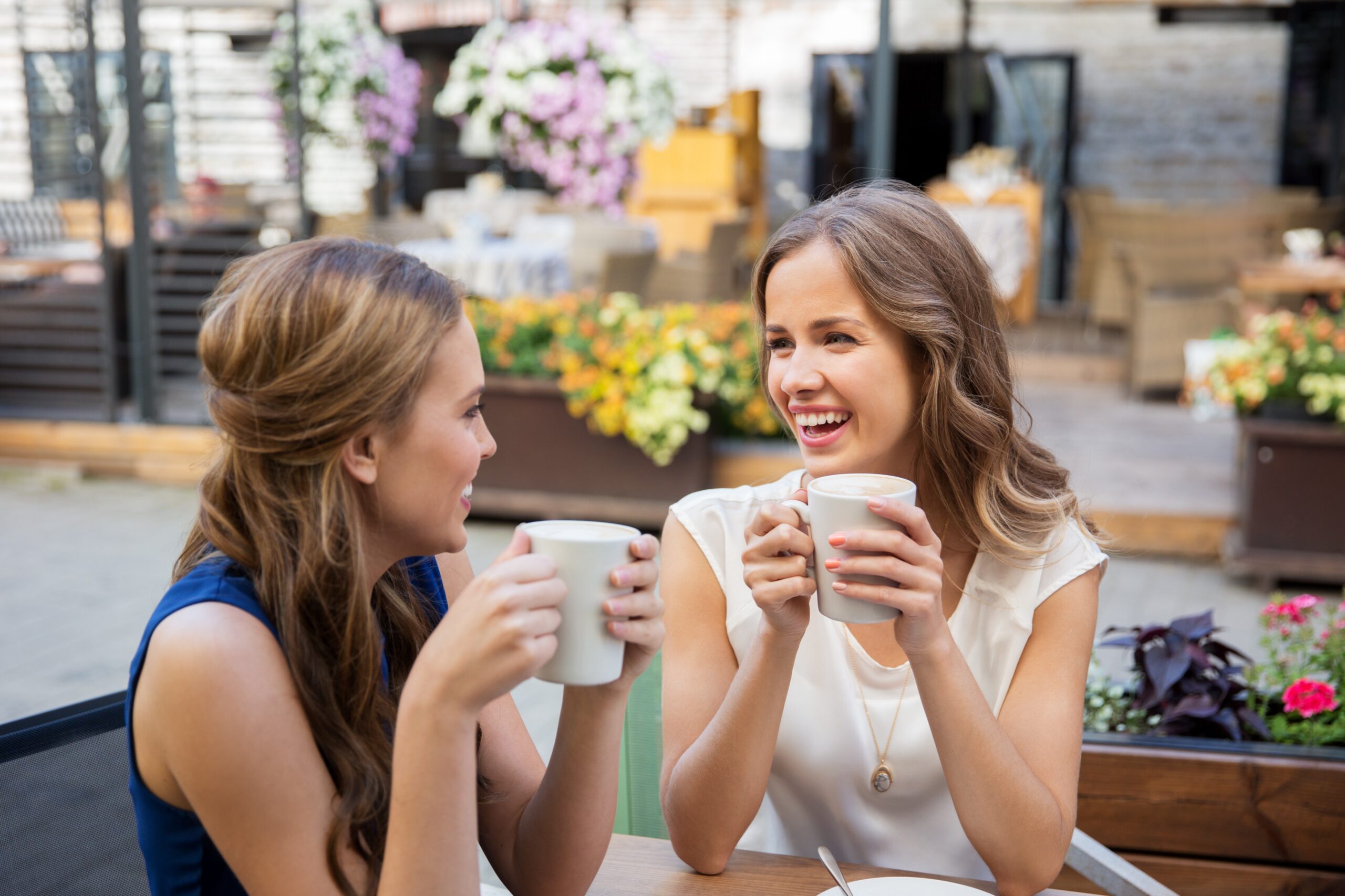 happy young women drinking coffee at outdoor cafe